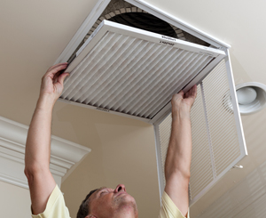 Senior man opening air conditioning filter in ceiling